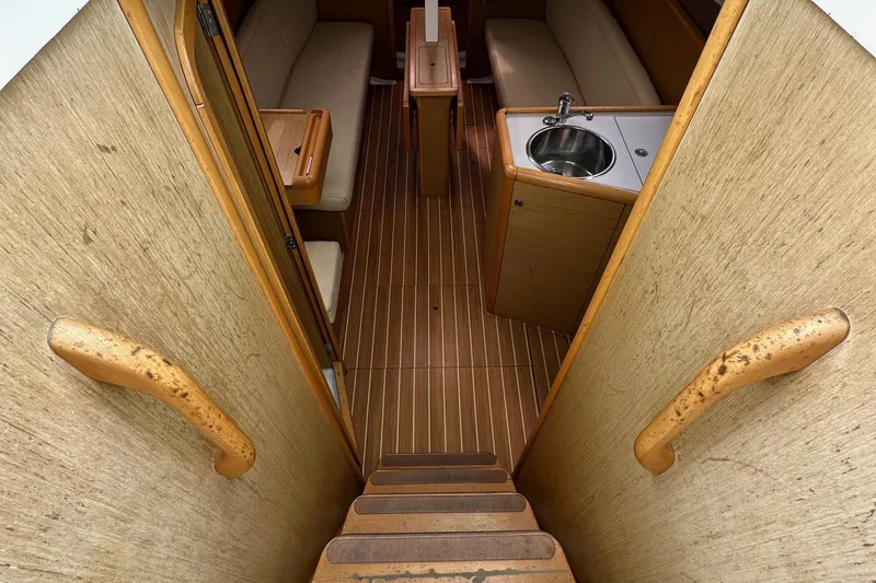 Slide: The Image of Interior of 2011 Jeanneau Sun Odyssey 33i sailboat, featuring wooden stairs, seating, and compact kitchen. - 39