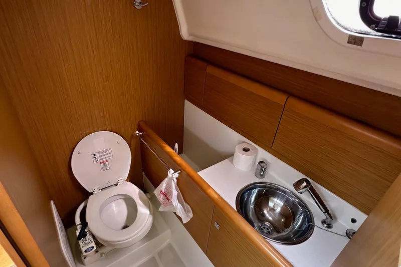 Slide: The Image of 2011 Jeanneau Sun Odyssey 33i yacht bathroom with toilet, sink, and wooden cabinetry. - 46