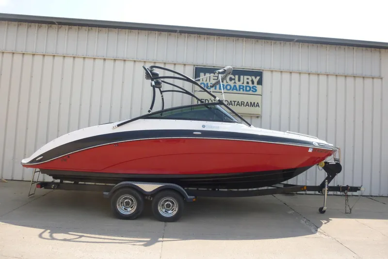 The Image of 2014 Yamaha Boats 240, red and white, on trailer outside a building. - 1