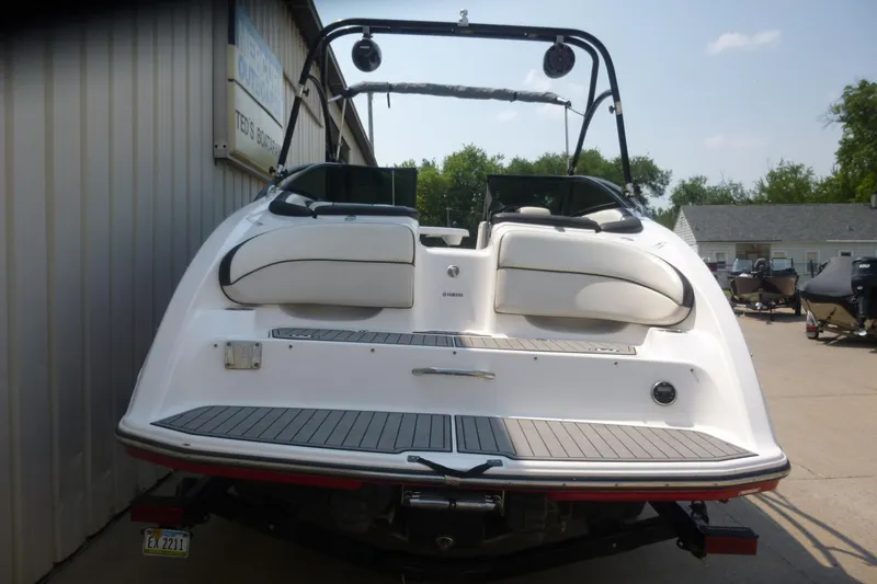Slide: The Image of 2014 Yamaha Boats 240, rear view, white exterior, docked near a building. - 17
