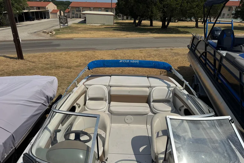 Slide: The Image of 2008 Four Winns H203 boat with open seating, parked on grass near buildings. - 23