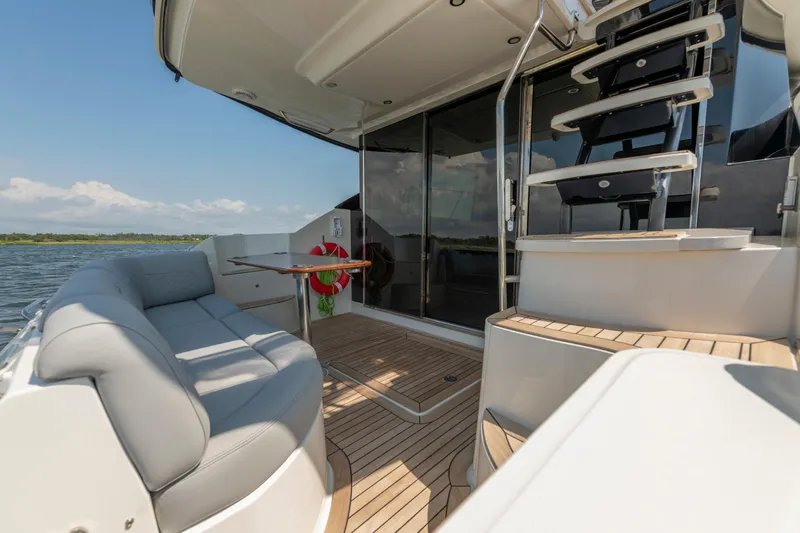 Slide: The Image of Luxurious 2017 Sea Ray Fly 510 yacht deck with seating and staircase, overlooking serene waters. - 17