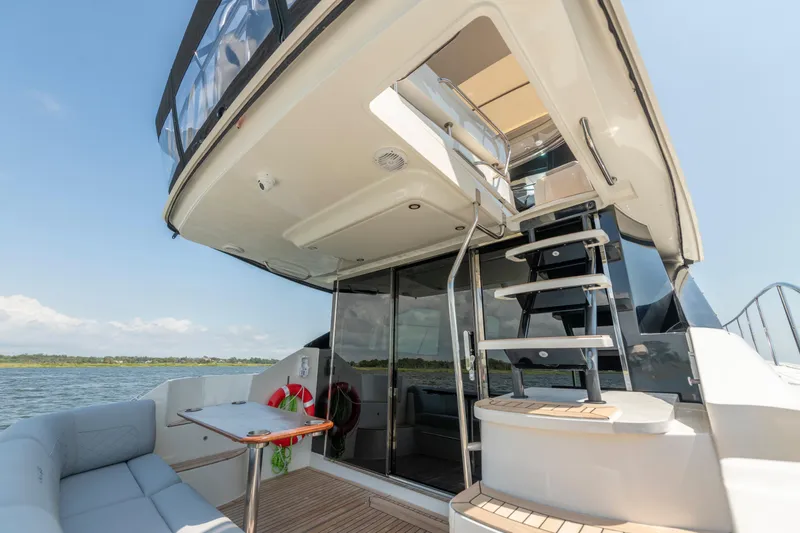Slide: The Image of 2017 Sea Ray Fly 510 yacht with outdoor seating and staircase, docked on a sunny day. - 18