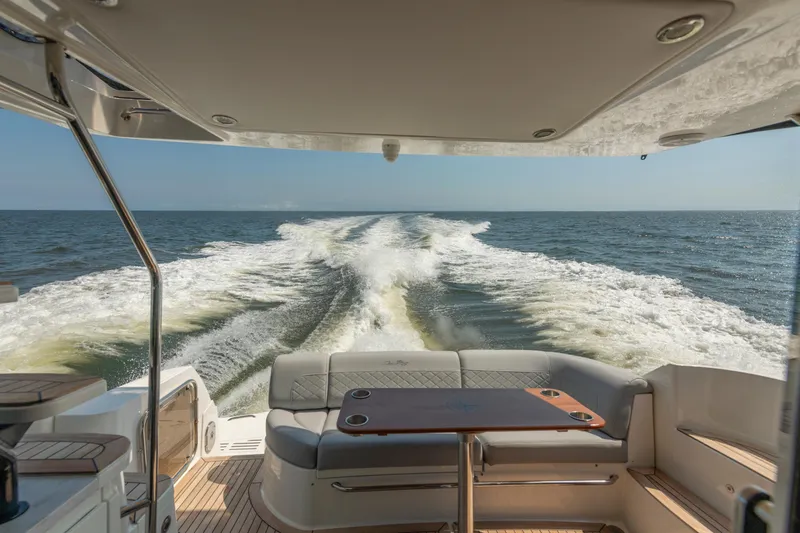 Slide: The Image of 2017 Sea Ray Fly 510 yacht cruising on open water, view from rear seating area. - 21