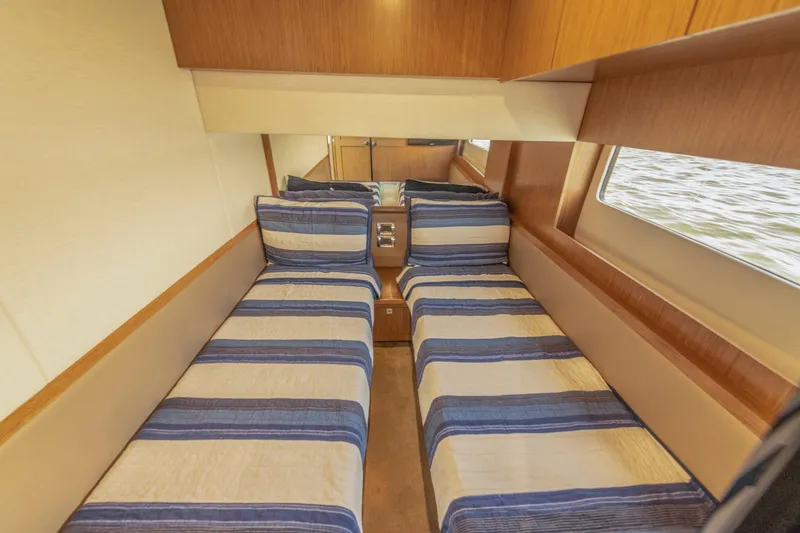 Slide: The Image of 2017 Sea Ray Fly 510 cabin with twin beds and striped bedding. - 65