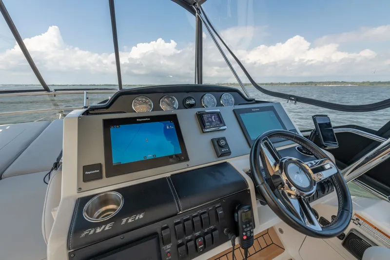 Slide: The Image of 2017 Sea Ray Fly 510 helm with navigation screens and steering wheel, overlooking the ocean. - 75