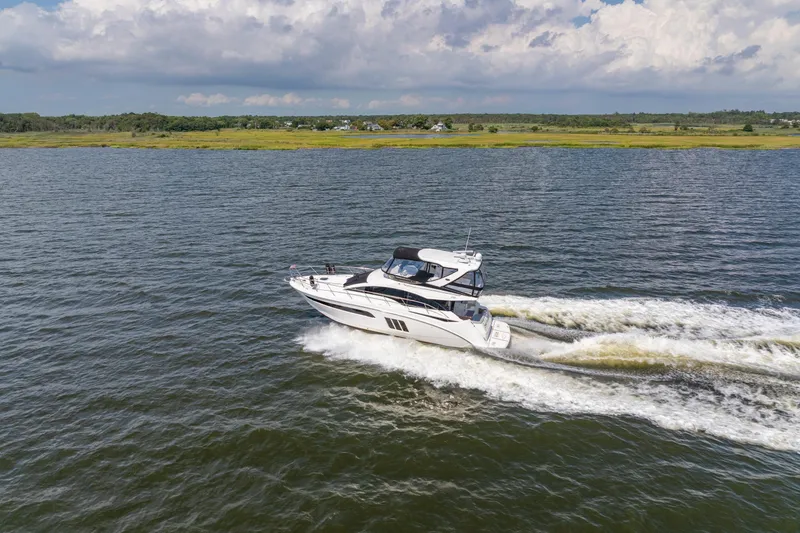 Slide: The Image of 2017 Sea Ray Fly 510 yacht cruising on open water under a partly cloudy sky. - 8