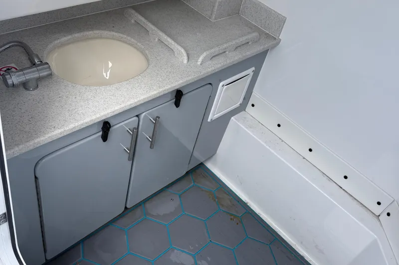 Slide: The Image of 2025 Stingray 253 CC boat interior with sink, countertop, and storage cabinets. - 11