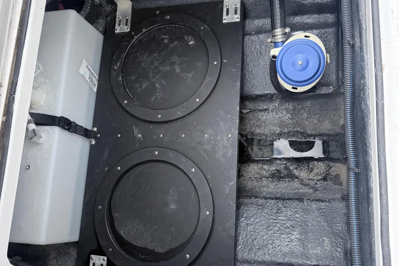 Slide: The Image of 2025 Stingray 253 CC boat storage compartment with dual circular hatches and a blue pump. - 5