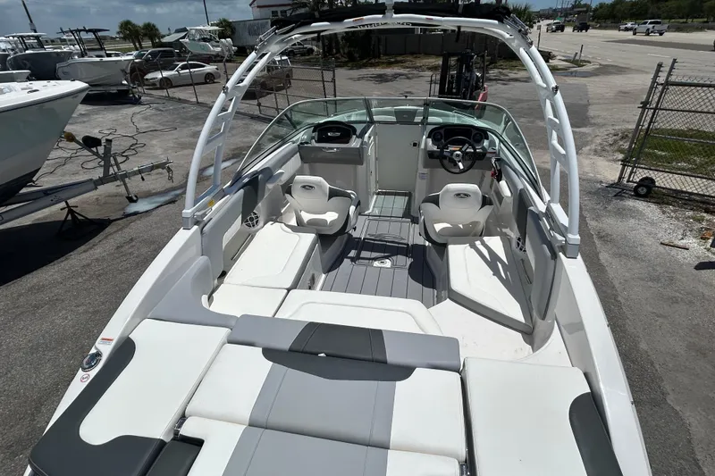 Slide: The Image of 2023 Chaparral 23 SSi OB boat interior with seating and steering wheel, parked outdoors. - 8