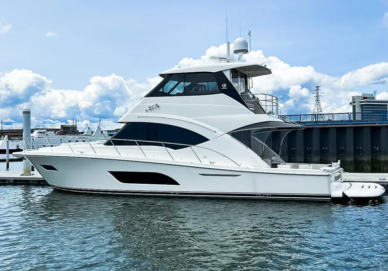 The Image of 2023 Riviera 57 Enclosed Flybridge yacht docked at marina under blue sky. - 0