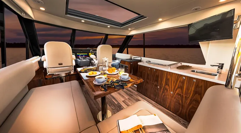Slide: The Image of Luxurious interior of 2023 Riviera 57 Enclosed Flybridge yacht with dining setup at sunset. - 10