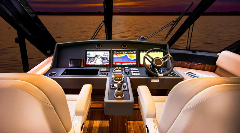 Slide: The Image of 2023 Riviera 57 Enclosed Flybridge helm with advanced navigation systems at sunset. - 11