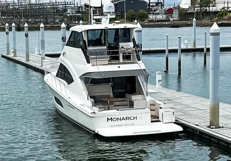 Slide: The Image of 2023 Riviera 57 Enclosed Flybridge yacht docked at marina, rear view. - 2
