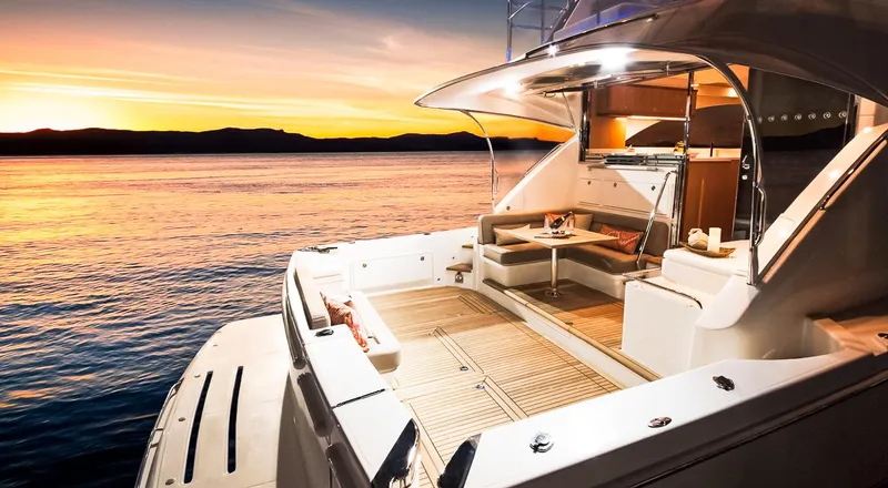 Slide: The Image of 2023 Riviera 57 Enclosed Flybridge yacht at sunset, featuring luxurious deck seating. - 4