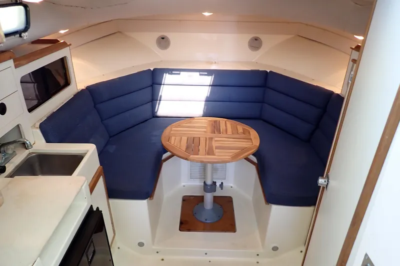 Slide: The Image of Interior of 2000 Albin 28 Tournament Express with blue seating and wooden table. - 10