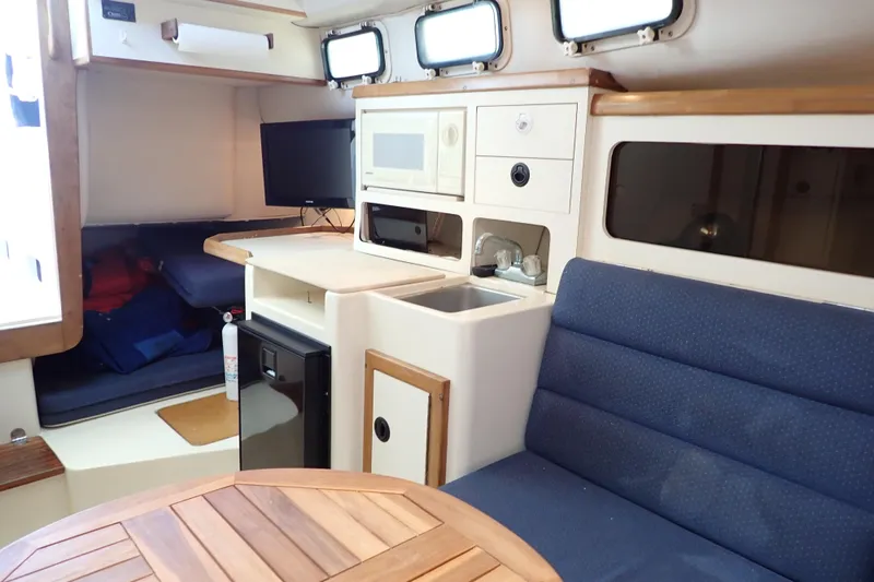 Slide: The Image of Interior of 2000 Albin 28 Tournament Express with kitchenette, seating, and portholes. - 11