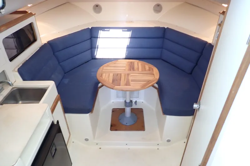 Slide: The Image of Interior of 2000 Albin 28 Tournament Express with blue seating and wooden table. - 37