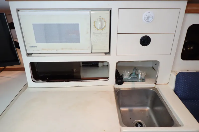 Slide: The Image of 2000 Albin 28 Tournament Express galley with microwave, sink, and storage compartments. - 45