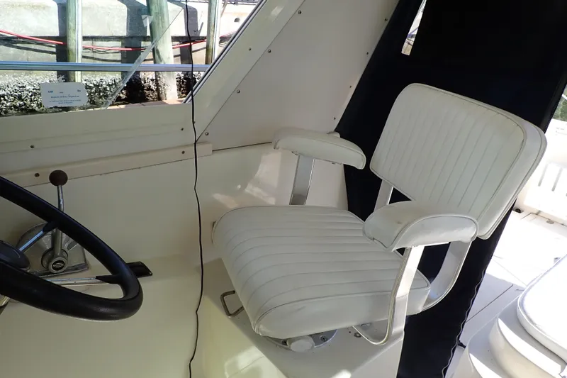 Slide: The Image of Captain's chair in 2000 Albin 28 Tournament Express boat cockpit, featuring steering wheel and controls. - 8