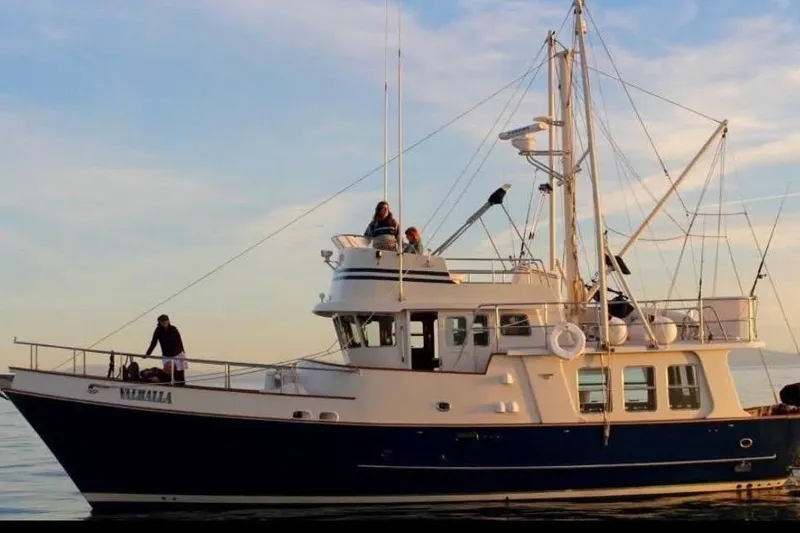 The Image of 1995 Nordhavn 46 yacht on calm water at sunset with people on deck. - 0
