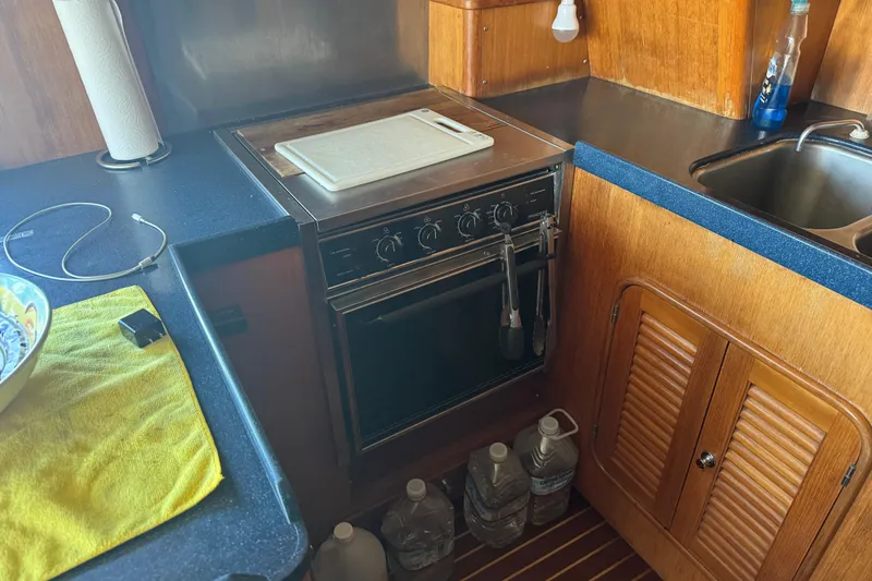 Slide: The Image of Galley kitchen in 1995 Nordhavn 46 yacht with stove, sink, and wooden cabinetry. - 12