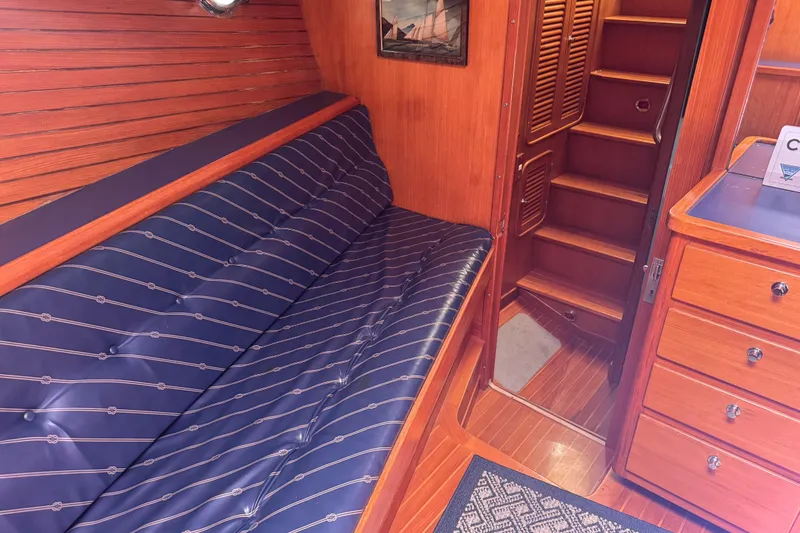 Slide: The Image of Interior of a 1995 Nordhavn 46 yacht with wooden paneling and blue cushioned seating. - 18