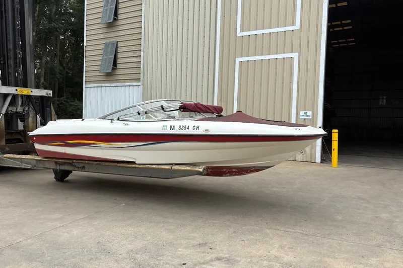 The Image of 2001 Bayliner 210 Classic boat on forklift near warehouse entrance. - 0
