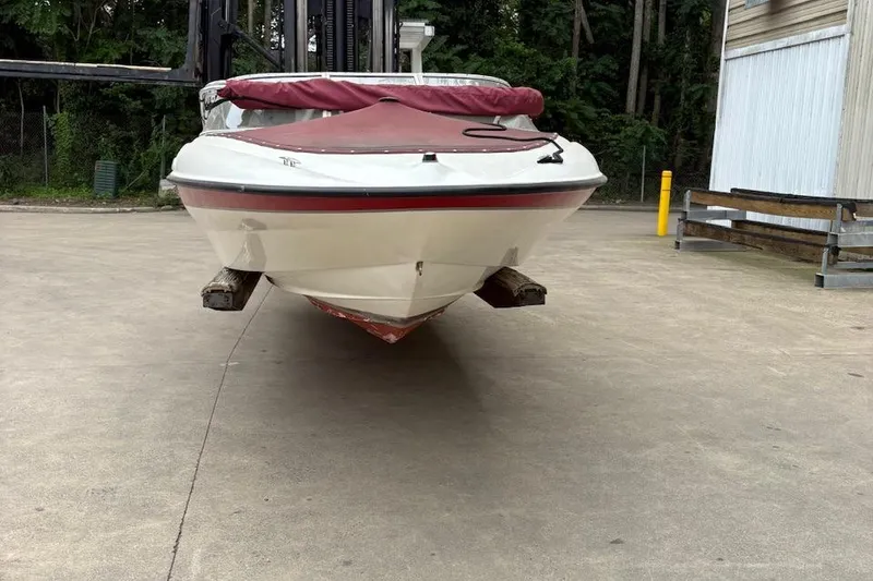 Slide: The Image of 2001 Bayliner 210 Classic boat with red cover, parked on concrete surface. - 1