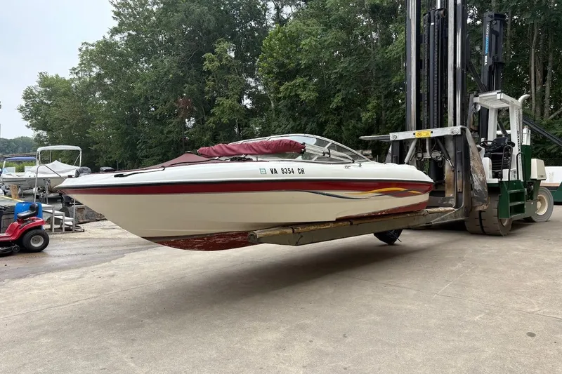 Slide: The Image of 2001 Bayliner 210 Classic boat lifted by forklift in outdoor setting. - 2