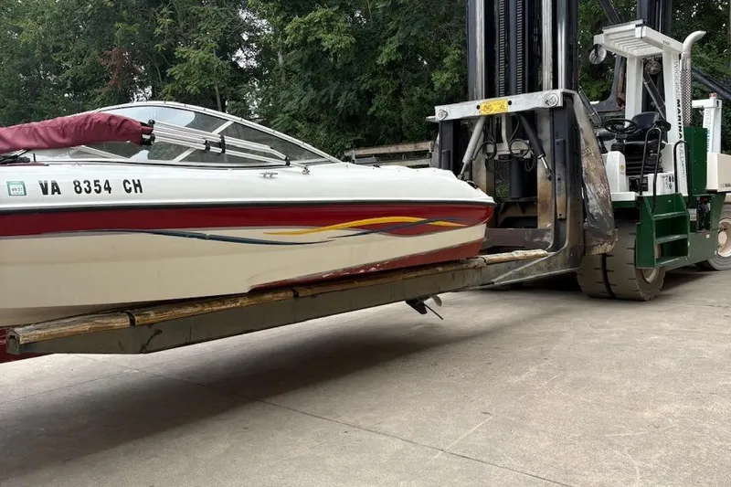 Slide: The Image of 2001 Bayliner 210 Classic boat being lifted by a forklift on a concrete surface. - 3
