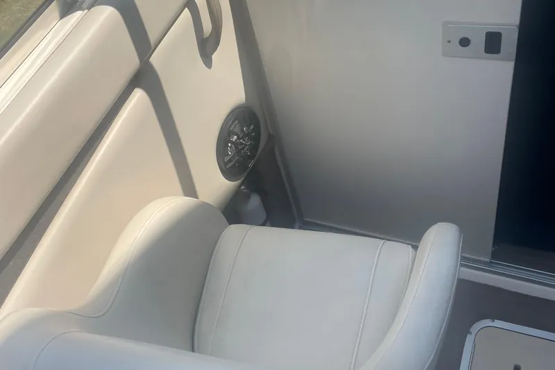Slide: The Image of Interior of a 1999 Bryant 214 Cuddy boat, featuring white seating and speaker. - 9
