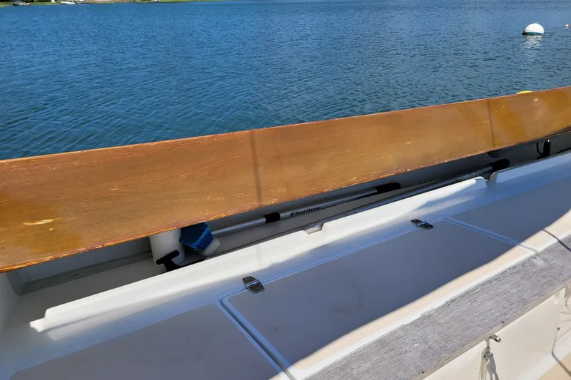 Slide: The Image of 2004 Alerion Express 28 sailboat deck with wooden rail, docked on calm water. - 14