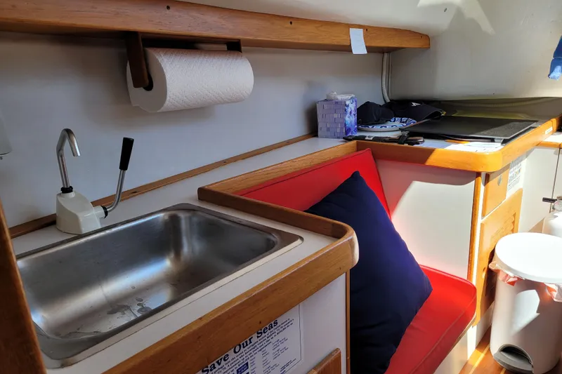 Slide: The Image of Interior of 2004 Alerion Express 28 sailboat with sink, red seating, and wooden accents. - 30
