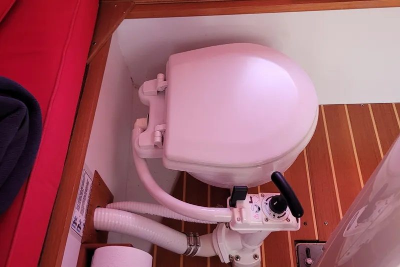 Slide: The Image of Marine toilet in 2004 Alerion Express 28 sailboat, featuring wooden flooring and red seating. - 31