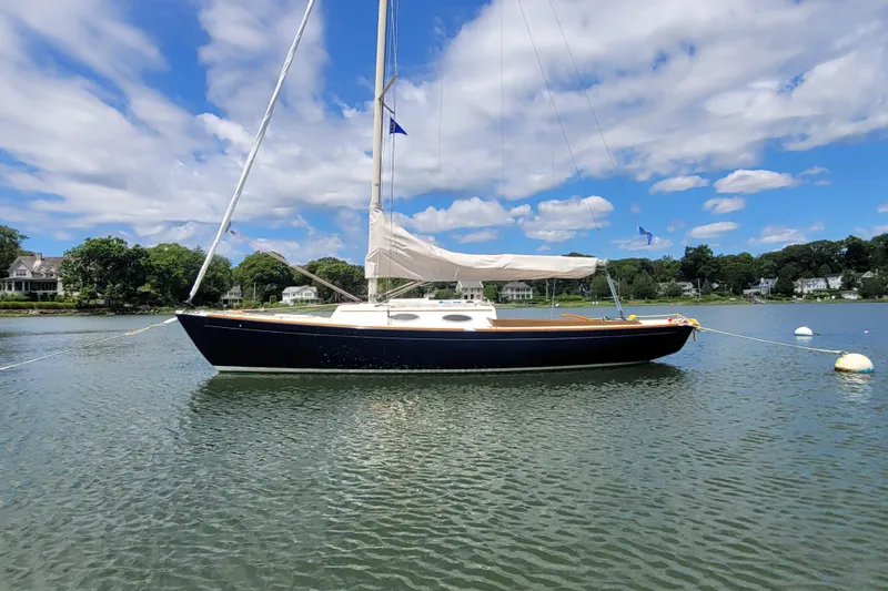 Slide: The Image of Alerion Express 28 sailboat from 2004 moored on a calm lake under a blue sky. - 8