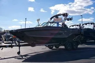 Slide: The Image of 2025 MasterCraft XT23 boat on trailer under clear blue sky. - 6