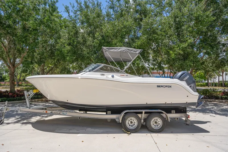 Slide: The Image of 2025 Sea Fox 228 Traveler boat on trailer, parked outdoors with trees in background. - 0
