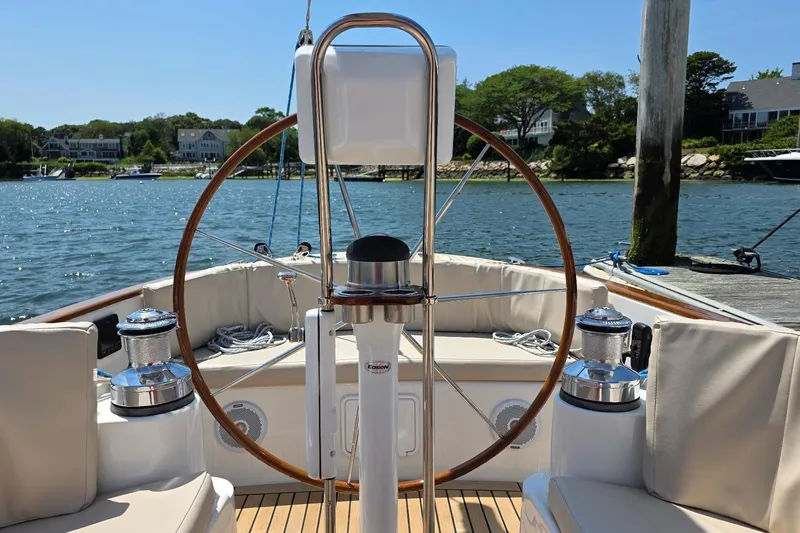 Slide: The Image of 2020 Alerion Express 33 sailboat cockpit with wooden wheel, docked by scenic waterfront homes. - 9