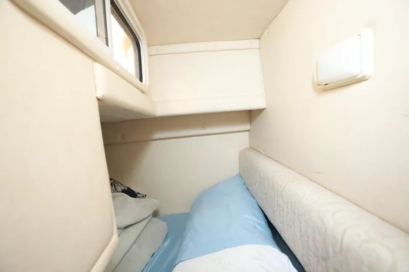 Slide: The Image of 2005 Sea Ray Sundancer 260 cabin interior with cozy sleeping area and window. - 12
