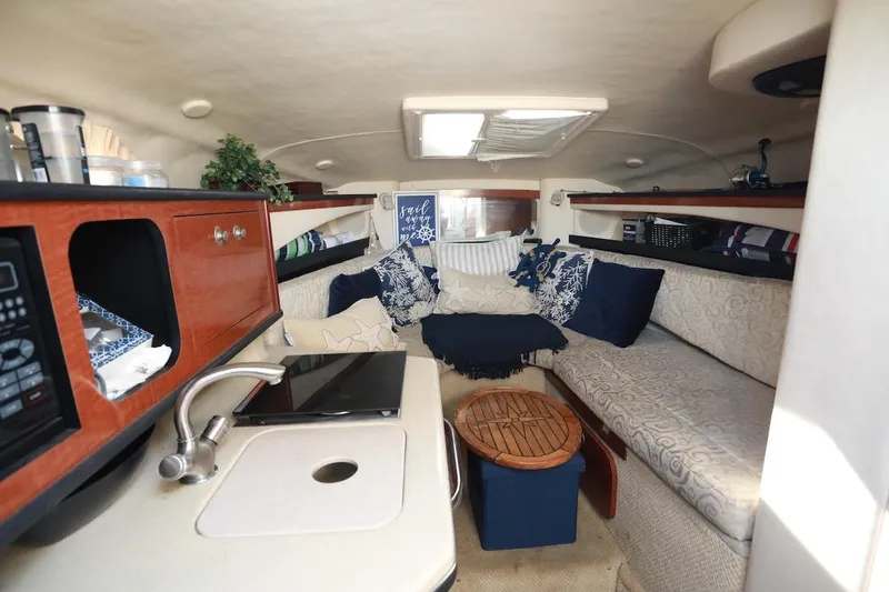 Slide: The Image of 2005 Sea Ray Sundancer 260 interior with kitchenette, microwave, sink, and cozy seating area. - 8