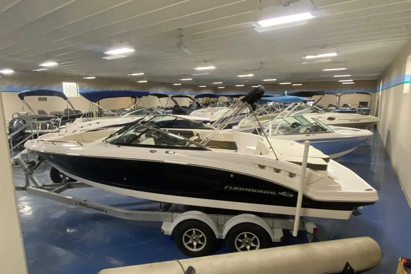 Slide: The Image of 2020 Chaparral 237 SSX boat in indoor showroom, displayed on a trailer. - 2