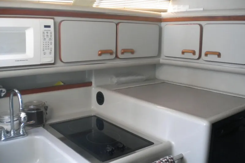Slide: The Image of 1990 Sea Ray 310 Sundancer kitchen with microwave, stove, and cabinets. - 13