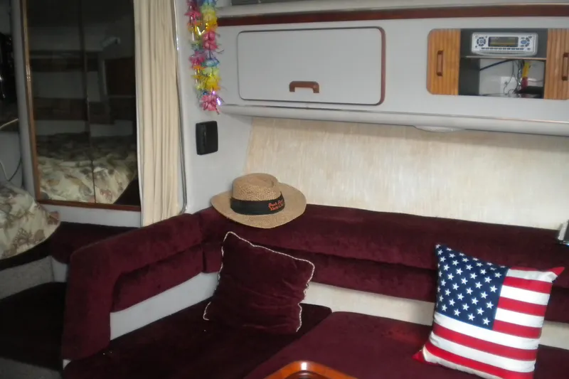 Slide: The Image of Interior of 1990 Sea Ray 310 Sundancer with maroon seating and American flag pillow. - 16