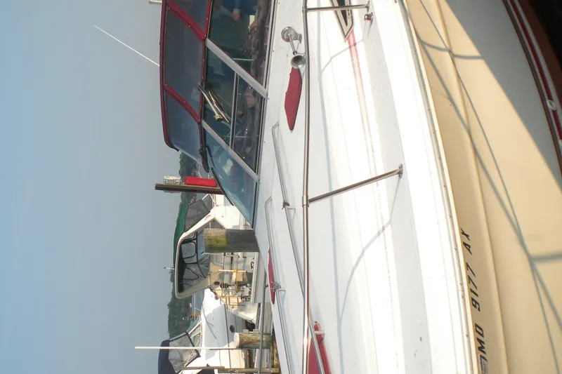 Slide: The Image of 1990 Sea Ray 310 Sundancer docked, featuring red canopy and sleek white design. - 20