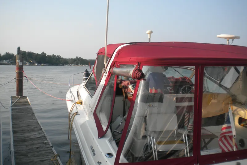 Slide: The Image of 1990 Sea Ray 310 Sundancer docked with red canopy, calm water, and American flag. - 4