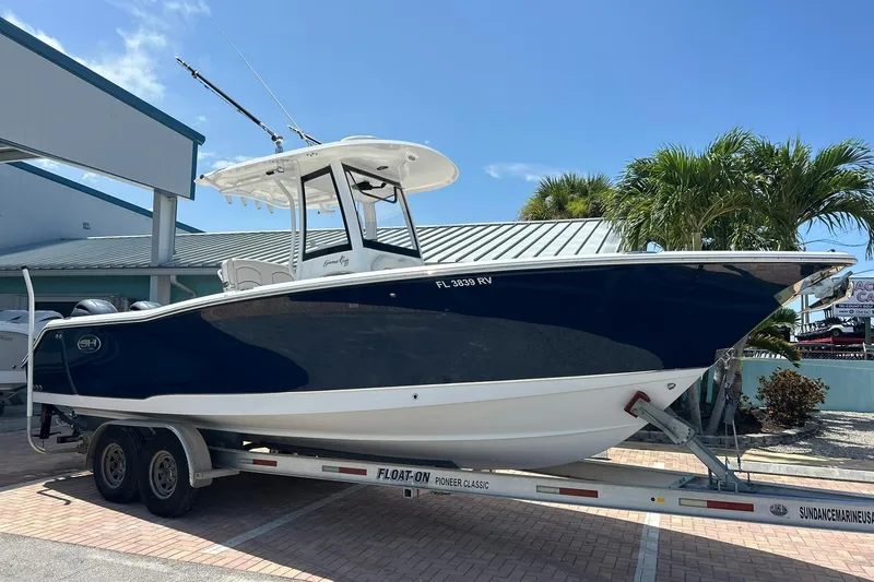 The Image of 2019 Sea Hunt Gamefish 27 boat on trailer, parked outdoors under clear sky. - 1