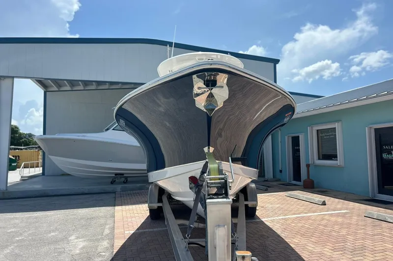 Slide: The Image of 2019 Sea Hunt Gamefish 27 boat on trailer, parked outside dealership under clear sky. - 2