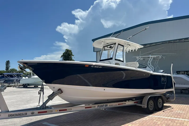 Slide: The Image of 2019 Sea Hunt Gamefish 27 boat on trailer, parked outdoors under a clear sky. - 3