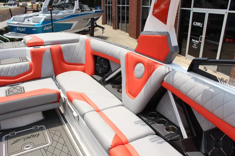Slide: The Image of 2020 Tigé 23ZX boat interior with orange and gray seating, cup holders, and modern design. - 10